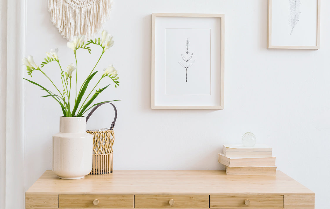 Cream white artificial freesia flower in a white vase, which underlines the desk decor is more artistic.