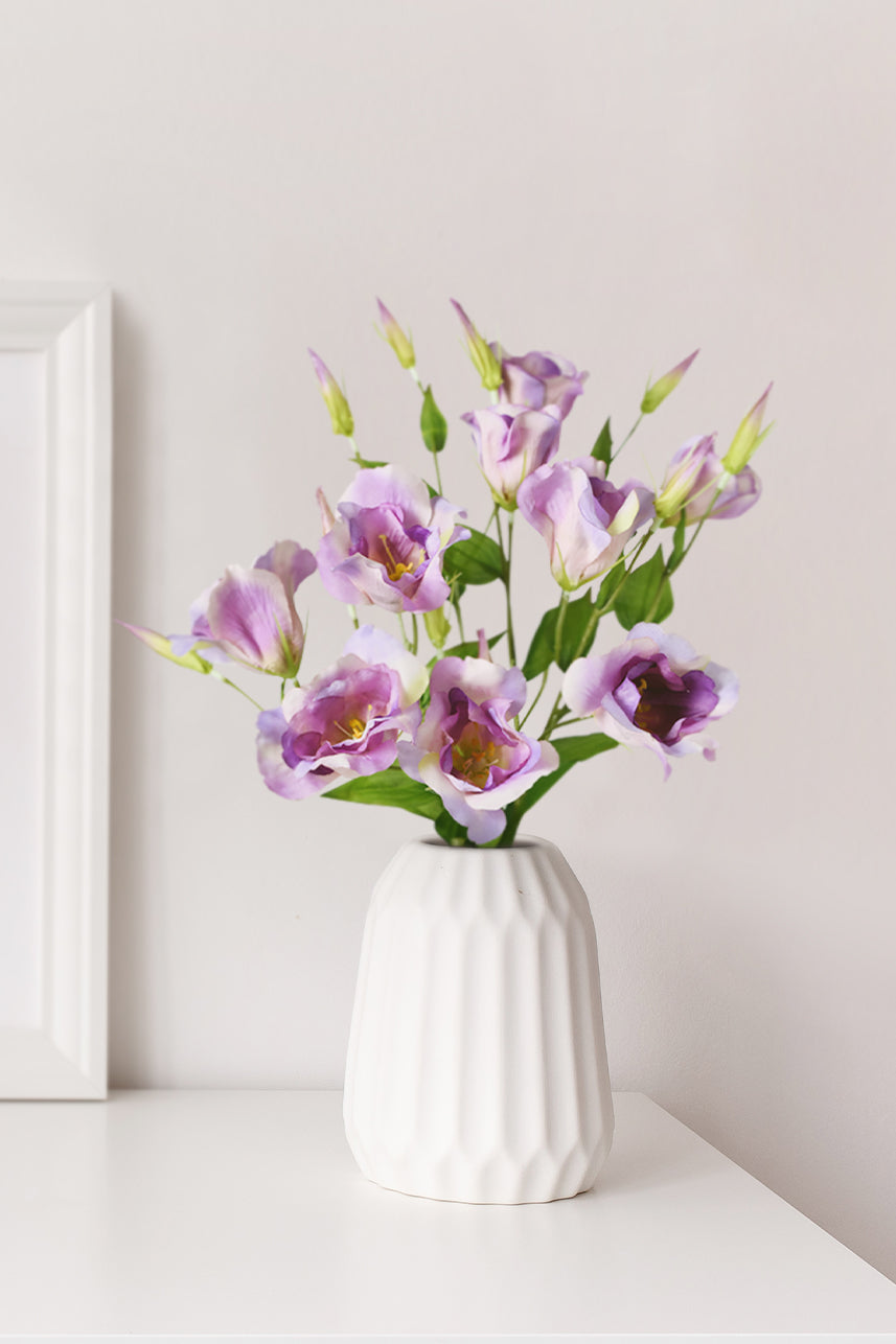 Vibrant and lifelike artificial lisianthus blooms in a stunning fuchsia pink color, beautifully displayed in a vase on the table.