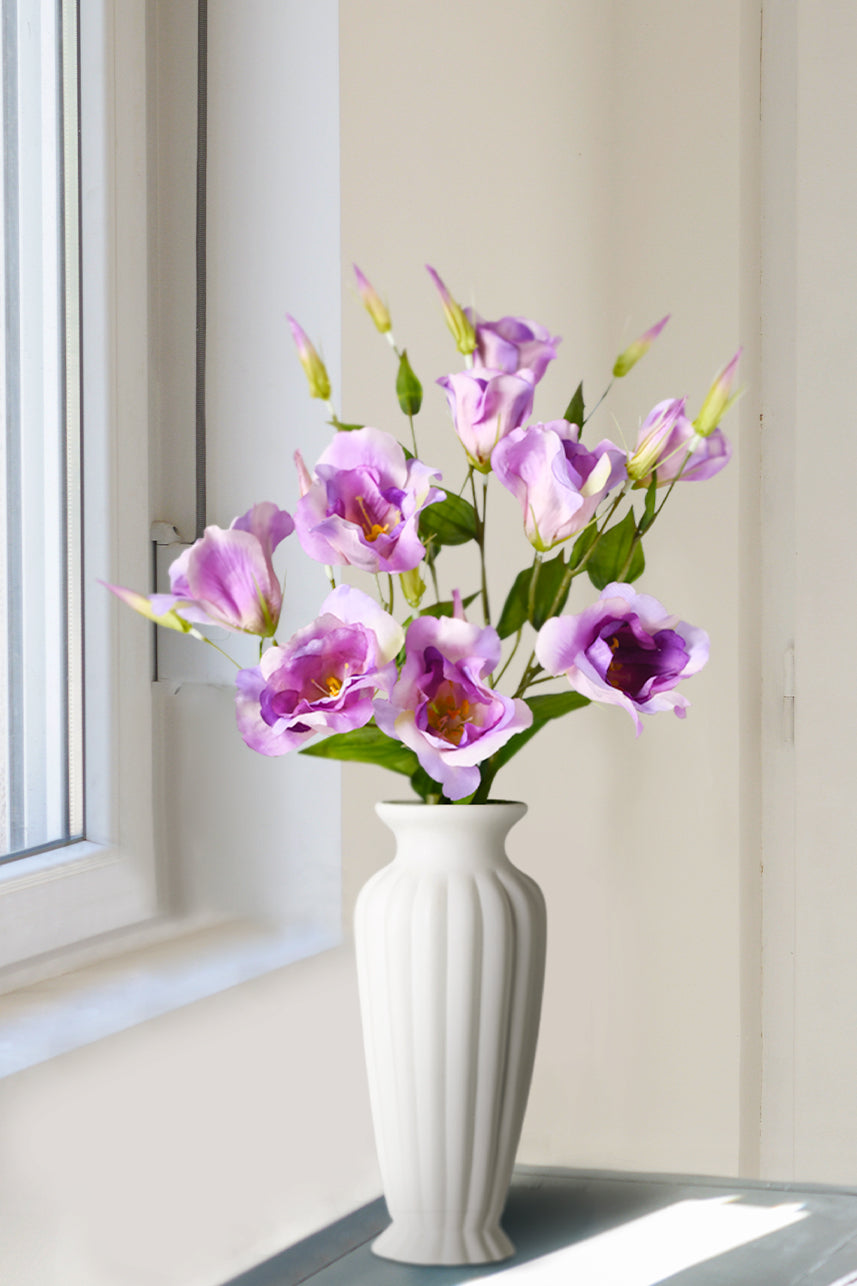 There is a vase with fake flowers by the window, the fake flowers bloom to simulate the natural growth of the plant, the faux flowers are full of color, suitable for making floral arrangements and bouquets.