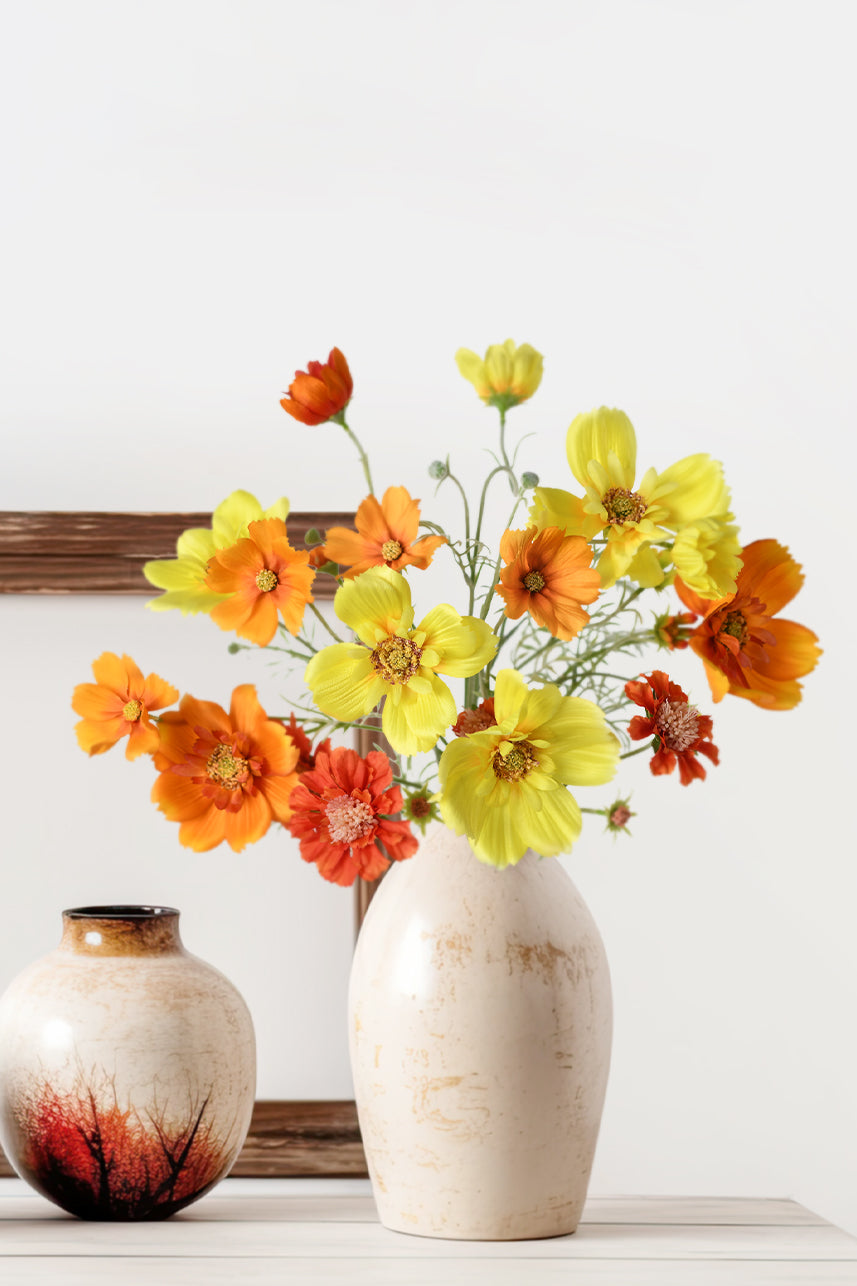 Artificial floral arrangements in warm colors are always eye-catching, and they make a perfect centerpiece when placed in a white vase.