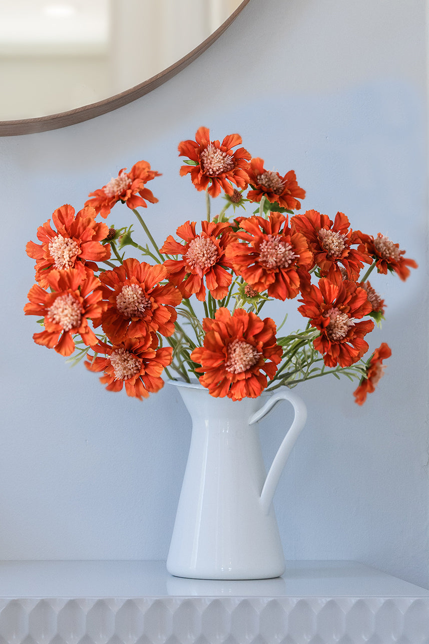 Bright orange faux Scabiosa Atropurpurea flower adds a touch of radiance to bathroom decor, infusing the space with vibrant beauty and a cheerful ambiance.