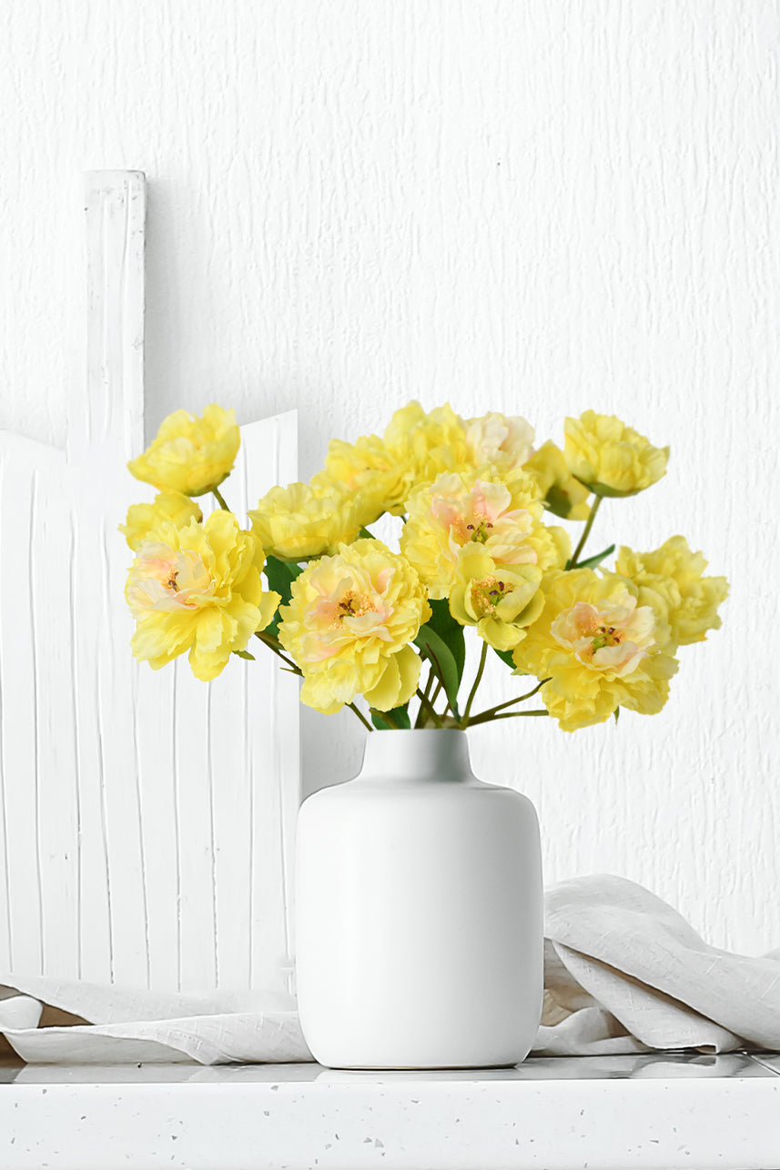 The yellow artificial peony flower is so vibrant and alive that it becomes a faux floral arrangement when placed in a white vase.