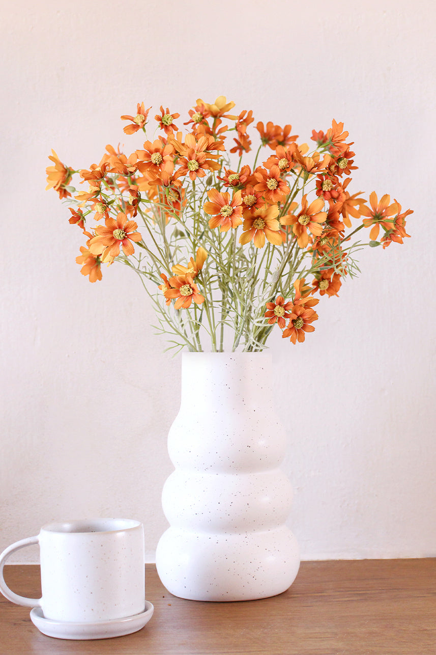 The artificial orange cosmos flower brings a burst of vibrant color to any space, infusing it with a sense of joy and energy.