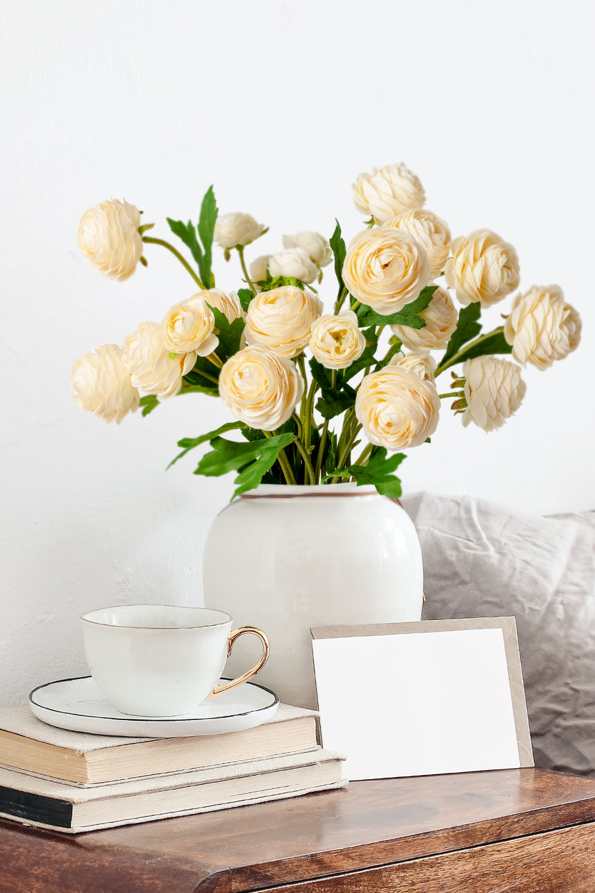 Sunny yellow Peach Ranunculus blooms radiate joy, artfully arranged in a pristine white vase for a burst of cheerful beauty.