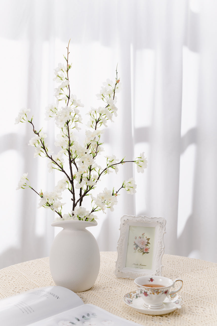 The budding to full bloom artificial cream white cherry blossom are complete with a white vase perfect as a centerpiece.
