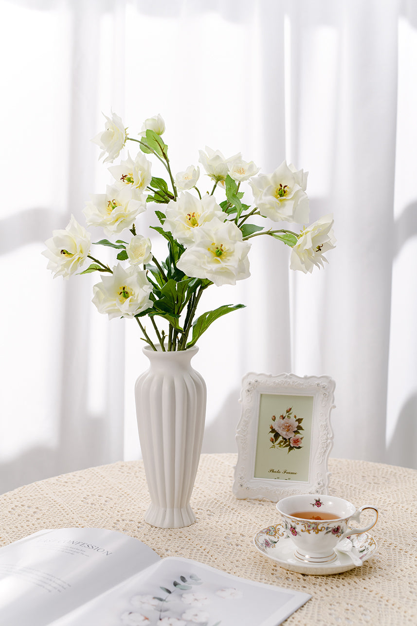 Artificial faux clematis are suitable for warm and comfortable home scenes, with fake flowers placed in white vases.