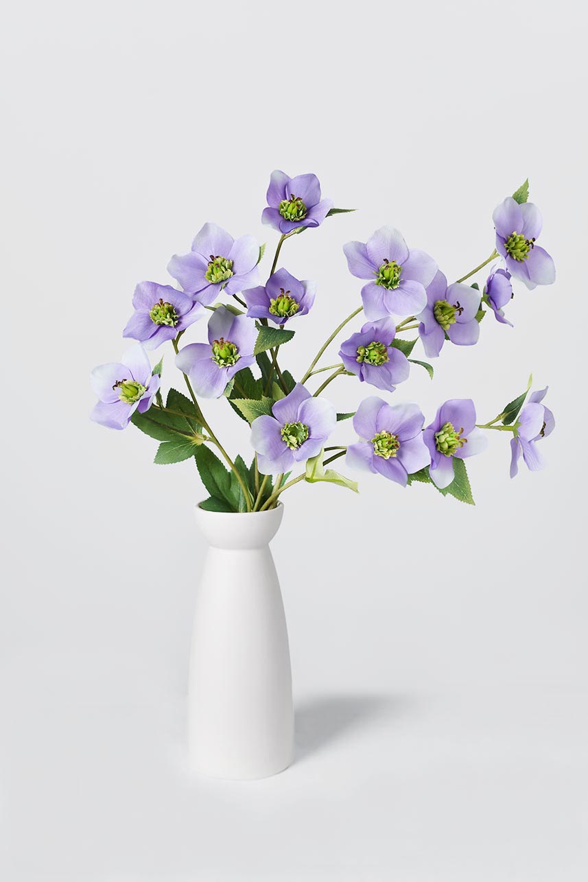 The budding to full bloom artificial light purple Helleborus silk blooms are complete with a white vase perfect as a centerpiece.