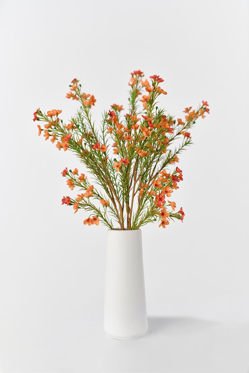 "Silkfloras faux blooming Chimonanthus Praecox in orange, arranged in a white vase for a stylish and natural decoration."