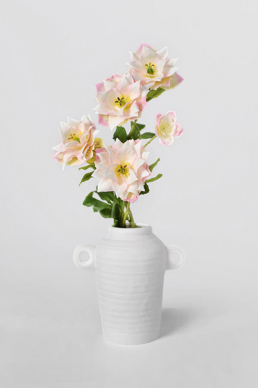 The mauve pink clematis is placed in a white vase, the flowers look like they are growing freely and it makes a stunning floral arrangement.