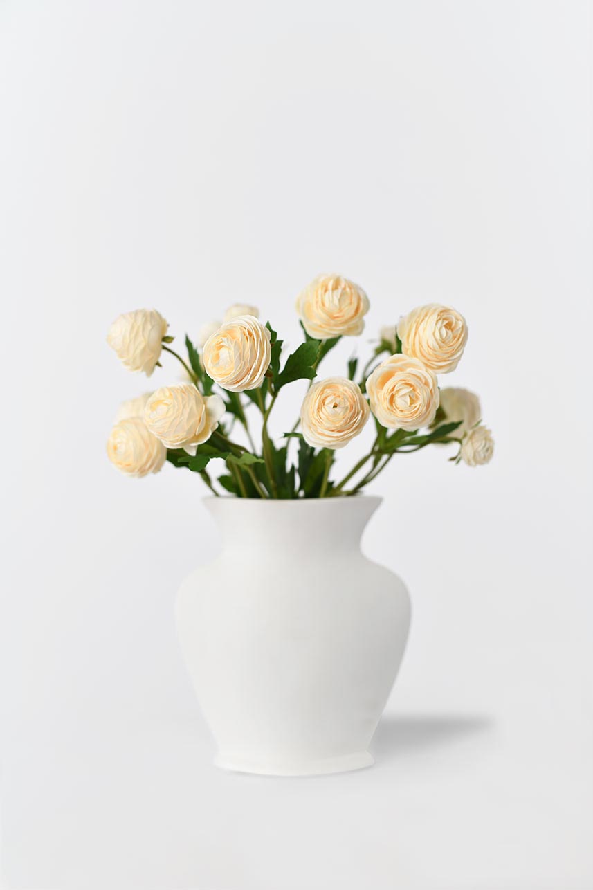 Artificial silk flowers in yellow peach with bright green leaves arranged in a vase, creating a blooming effect