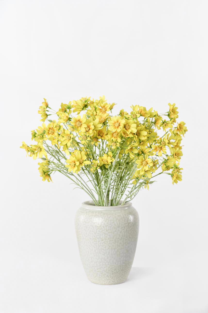 Artificial yellow Cosmos flowers arranged in a vase, adding natural charm to any space.