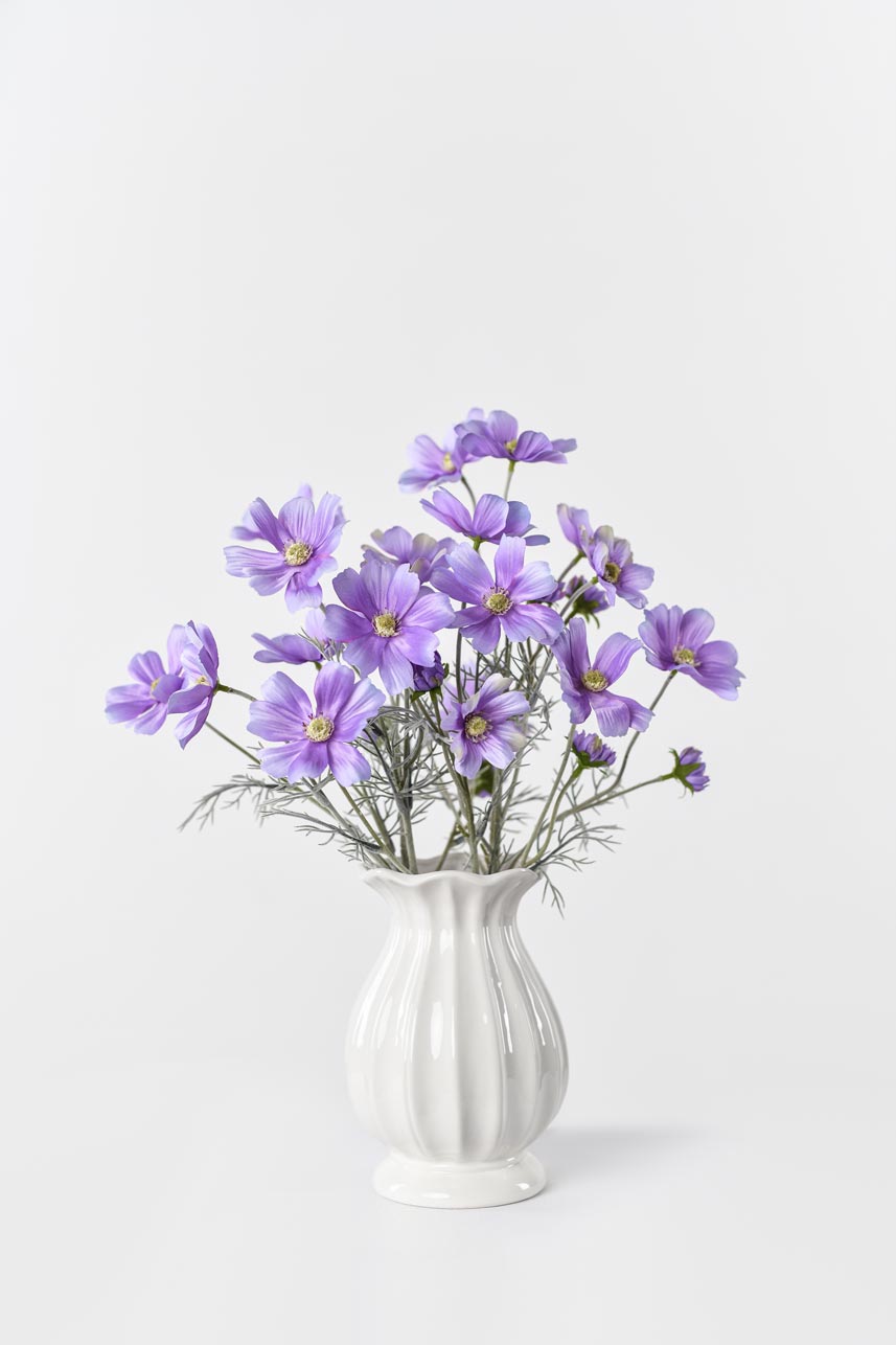 A vase filled with light purple Faux Cosmos flowers, adding a touch of elegance and charm to any space.