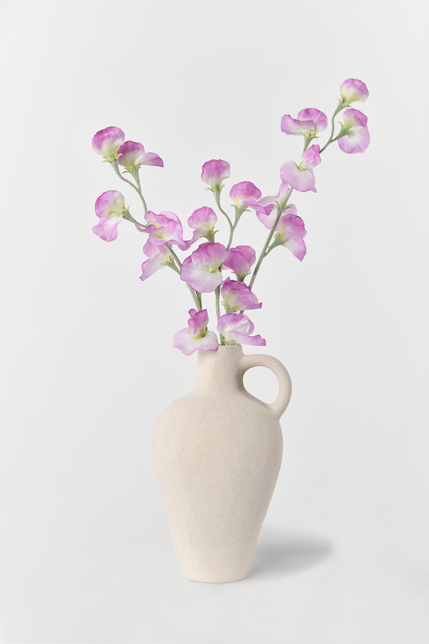 A vase filled with floating light purple artificial lathyrus odoratus flowers, perfect for creating a serene and calming atmosphere.