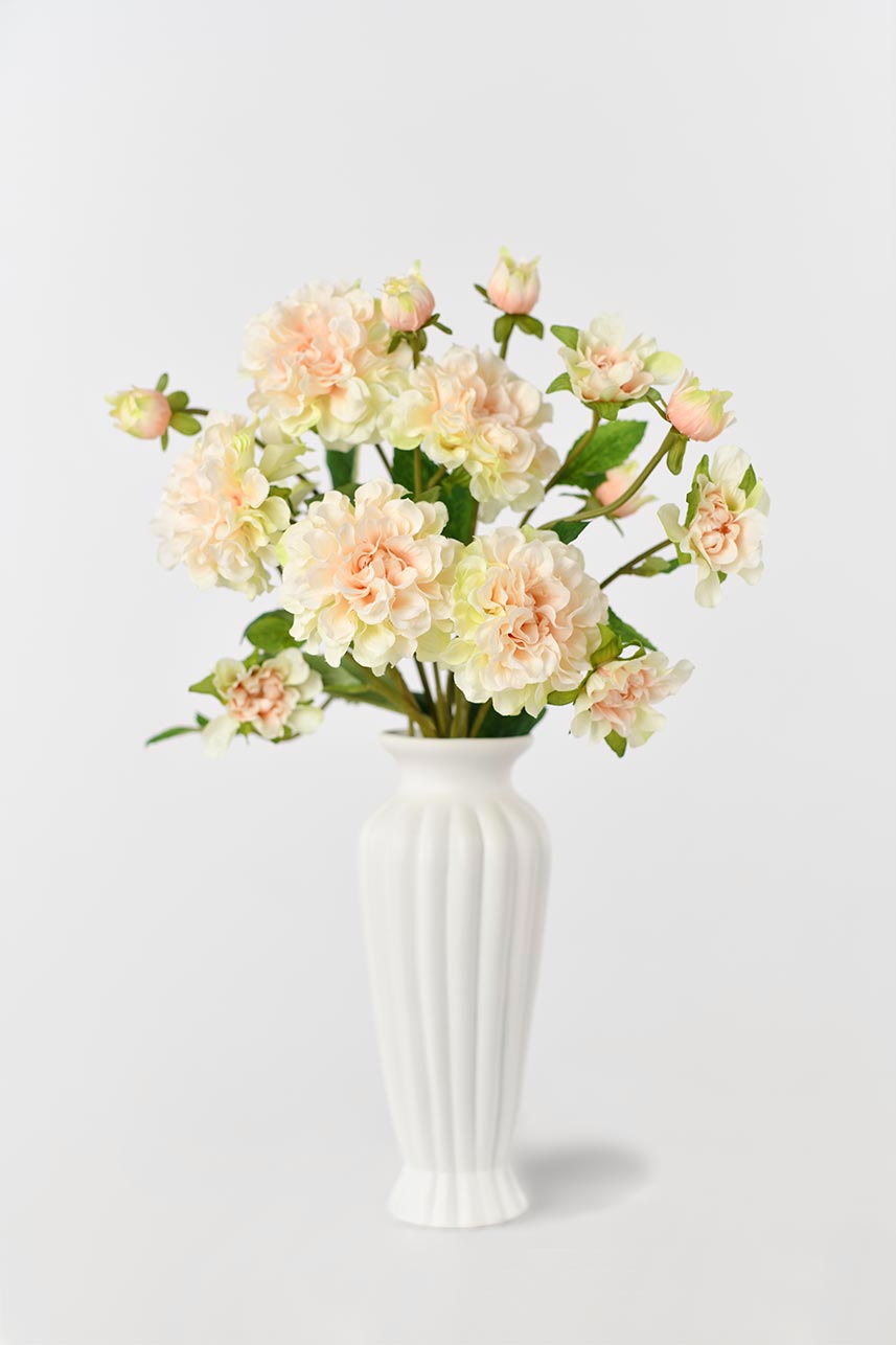 A decorative vase filled with realistic-looking silk peony flowers in a blush peach color, perfect for adding a touch of elegance to any room.