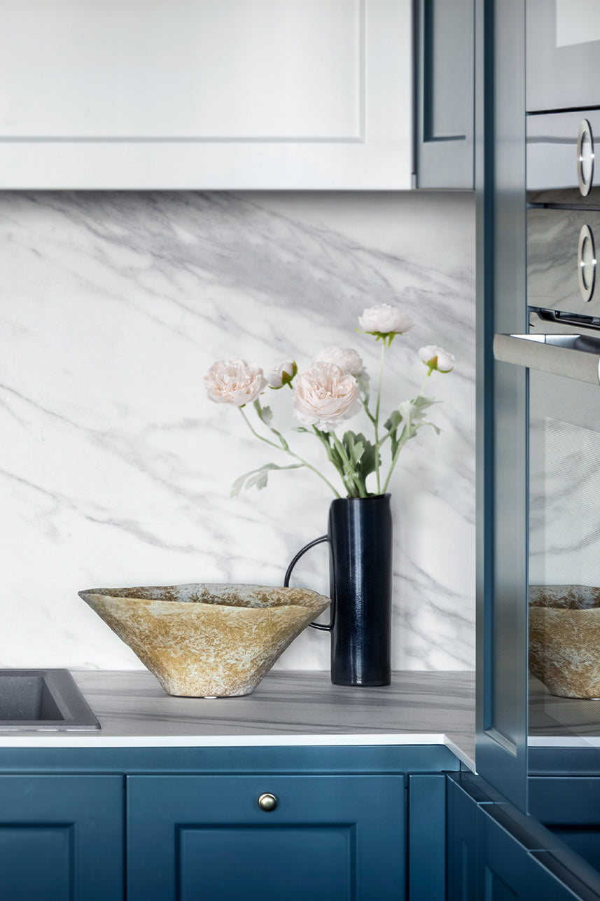 In the kitchen, a charming arrangement of light pink artificial Ranunculus flowers graces a blue vase, adding a touch of floral elegance to the space.