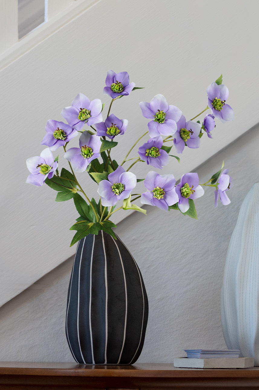 Light purple fake Helleborus silk floral arrangement beautifully adorns the staircase decor in a sleek black vase, adding a touch of elegance and charm.