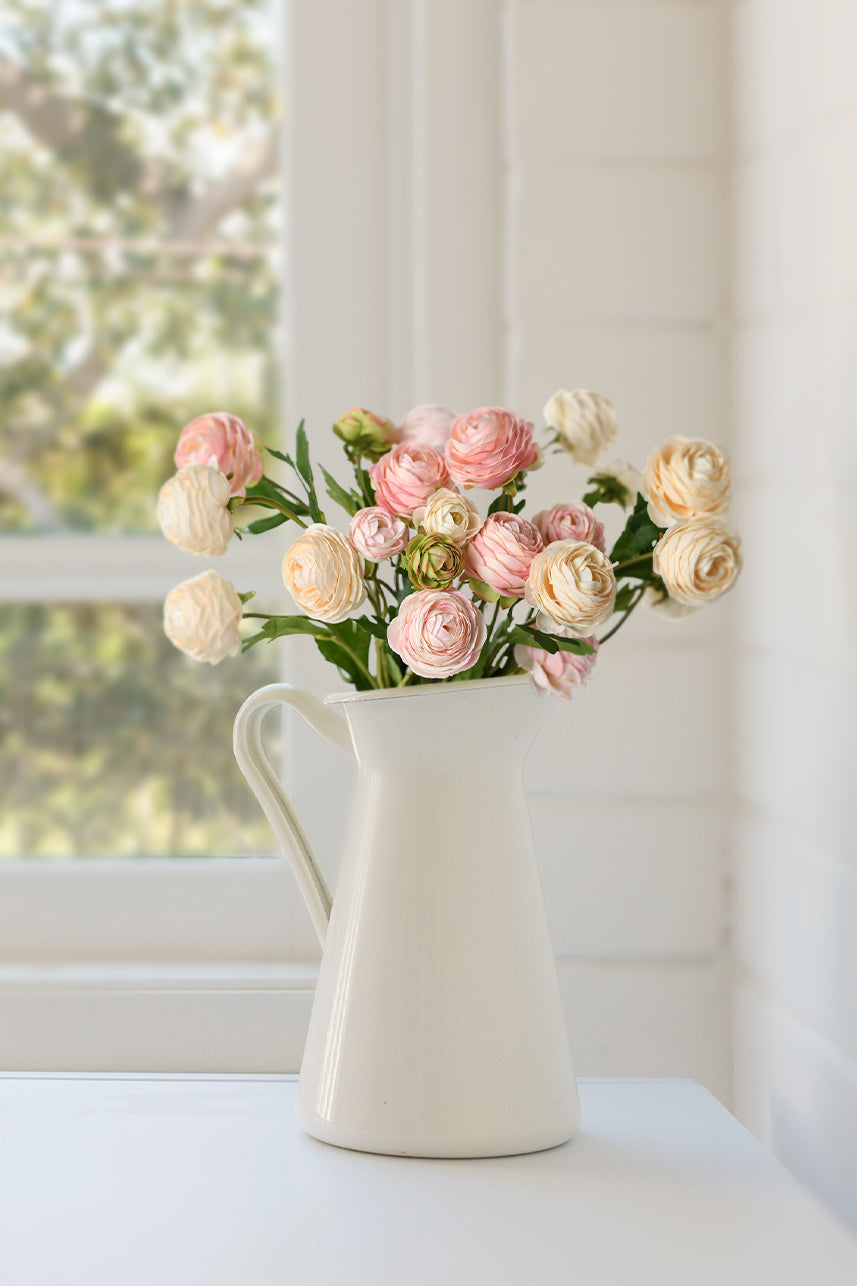 The many colors of artificial ranunculus make a beautiful floral arrangement, which can be placed in a white vase.