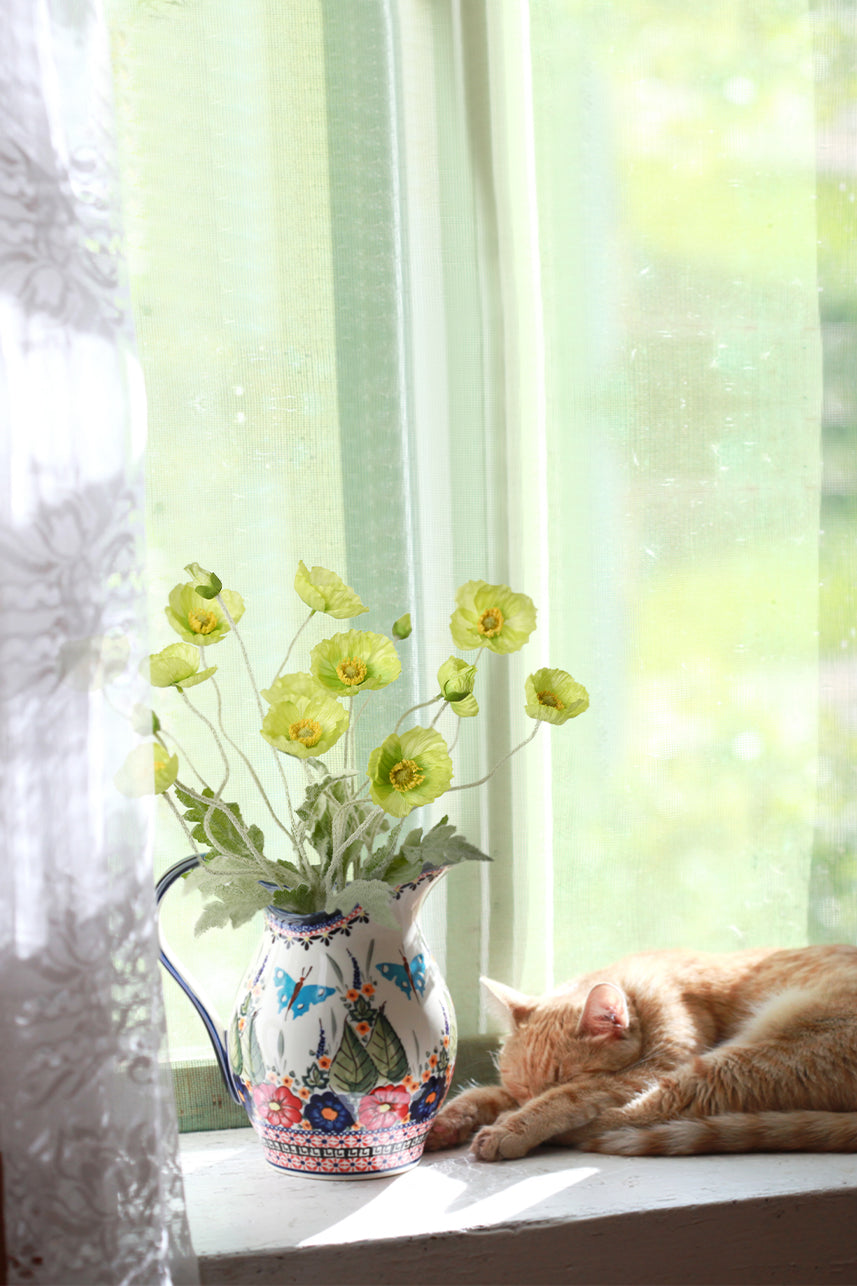 Adorn your windowsill with the vibrant beauty of fake Papaver Rhoeas flowers in soft-green, accompanied by a peacefully sleeping cat.