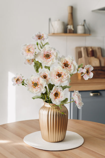 A beautiful artificial faux flower arrangement becomes the perfect home decoration, with soft pink faux lotus crane peonies placed in a metal vase.