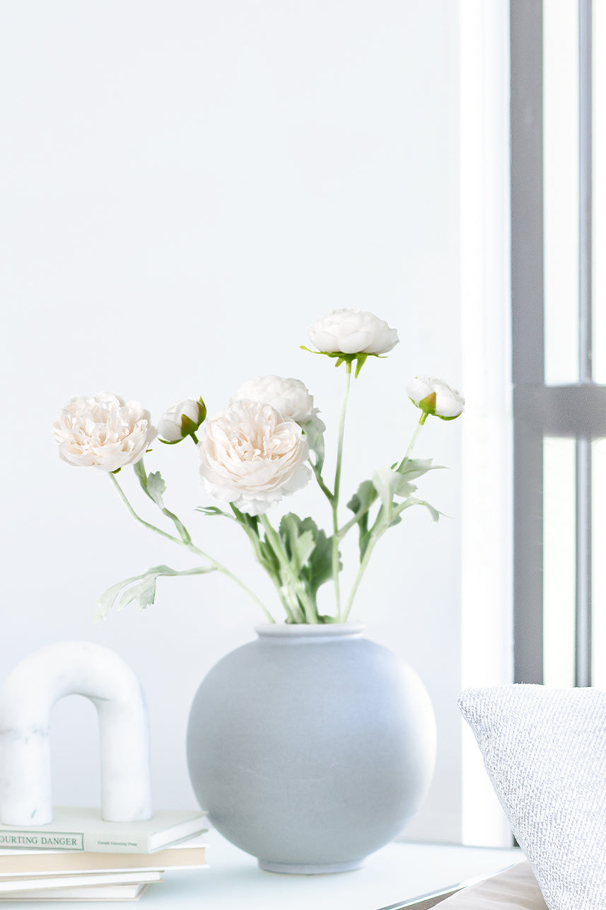The budding to full bloom artificial Ranunculus fake flowers are complete with a white vase perfect as a centerpiece.