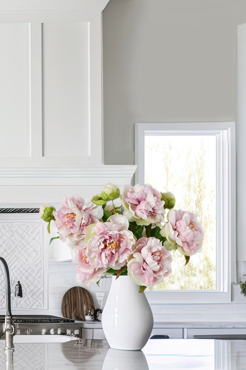 A stunning decorative faux flower arrangement featuring a silk Phoenix peony in pastel lavender, pink and cream colors with lifelike petals and green leaves.