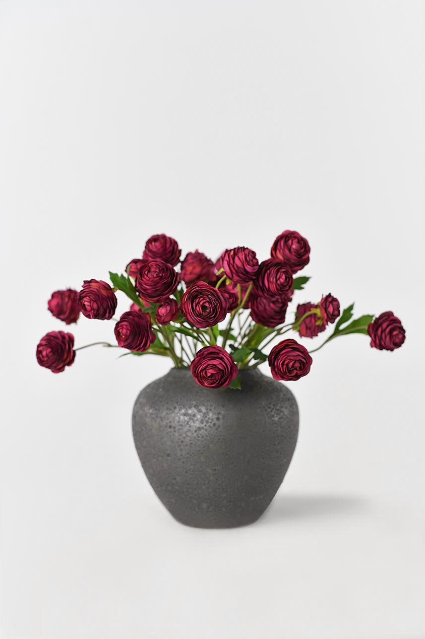 Artificial silk Ranunculus flowers arranged in a vase with other artificial flowers, in red color