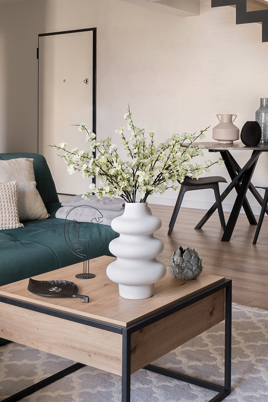 Artificial cream white cherry blossom arrangements in a white vase, under the stairs.