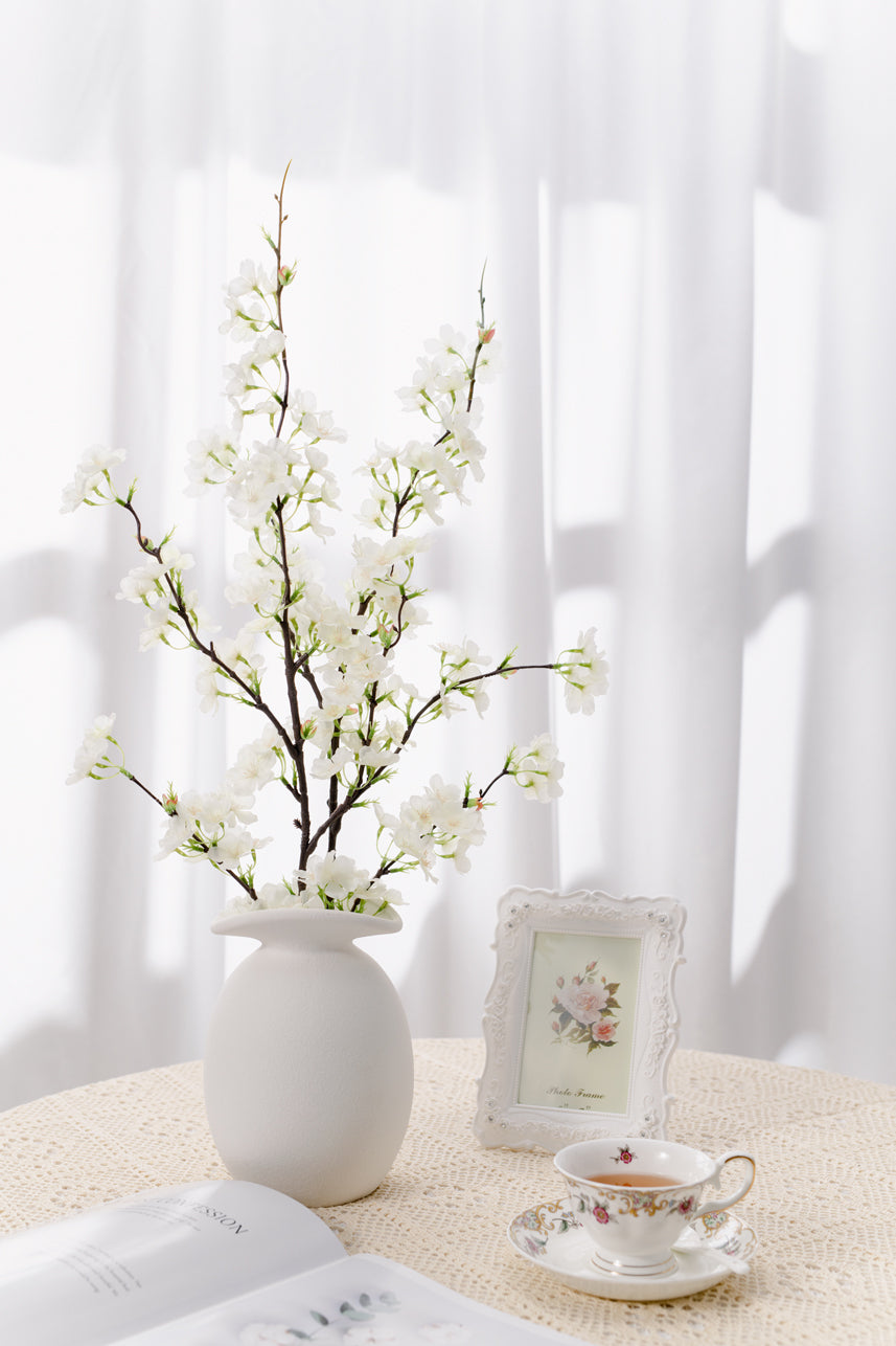 The budding to full bloom artificial cream white cherry blossom are complete with a white vase perfect as a centerpiece. 