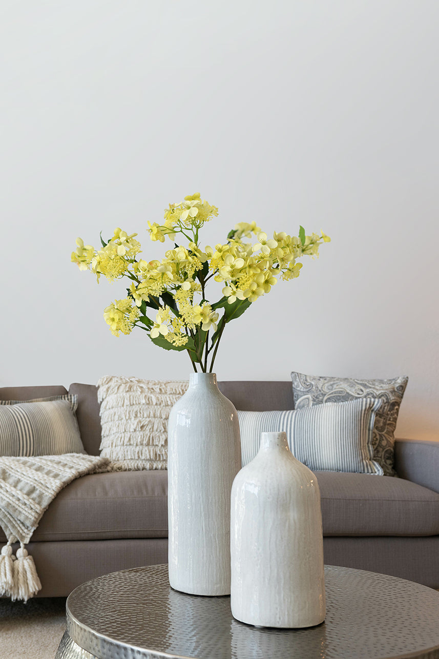 The yellow artificial hydrangea hortensia perfectly into the modern minimalist style of the home, and it is placed on the coffee table.