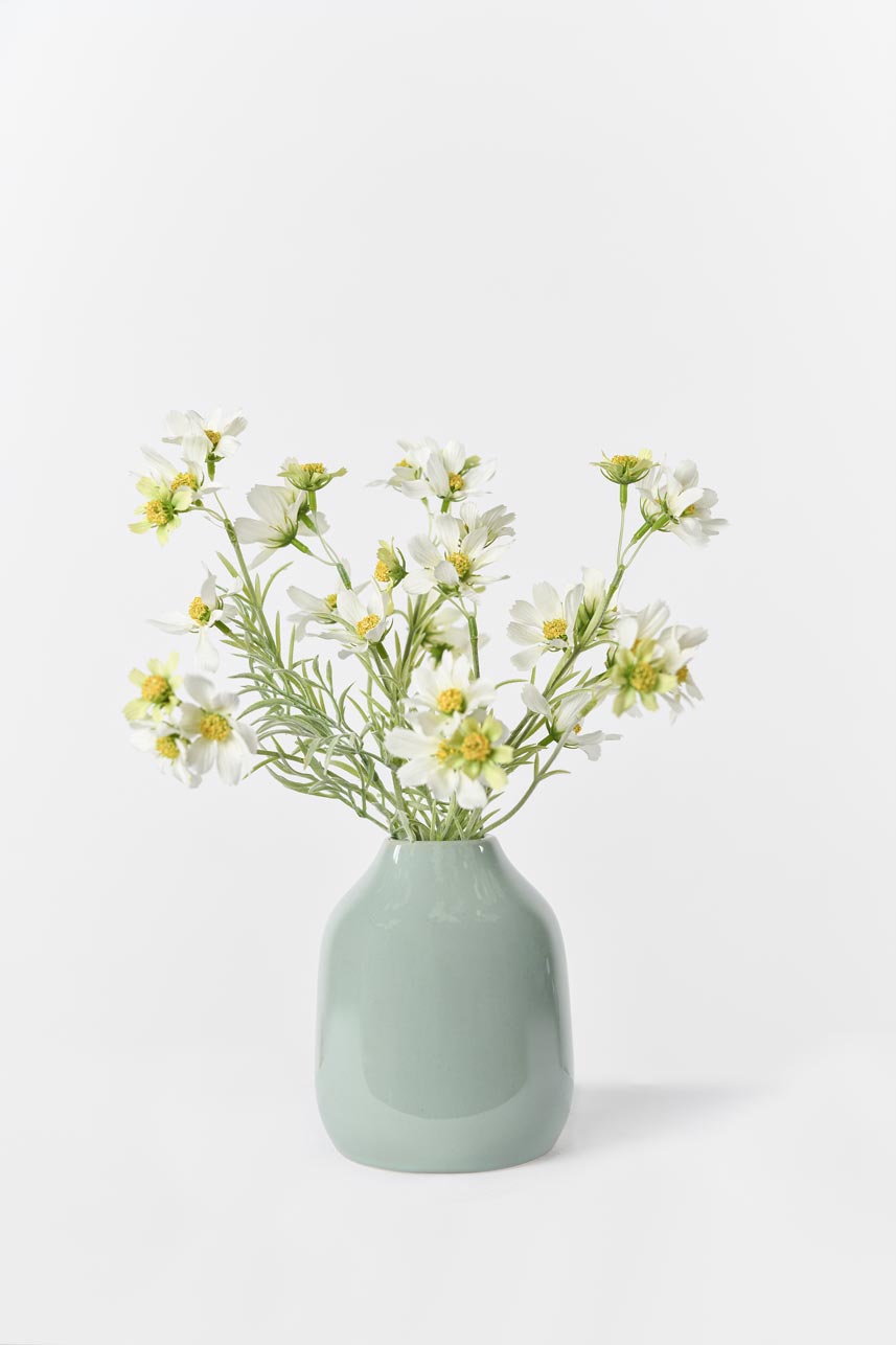 A vase filled with cream and white artificial cosmos flowers, arranged to create a beautiful display.