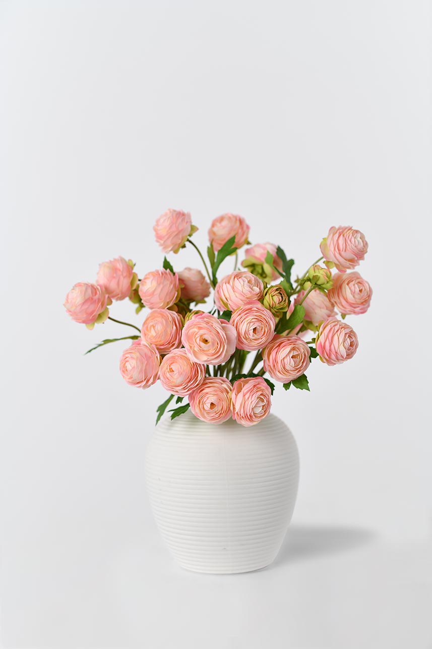 Artificial silk flowers in rose pink with bright green leaves arranged in a vase, creating a blooming effect