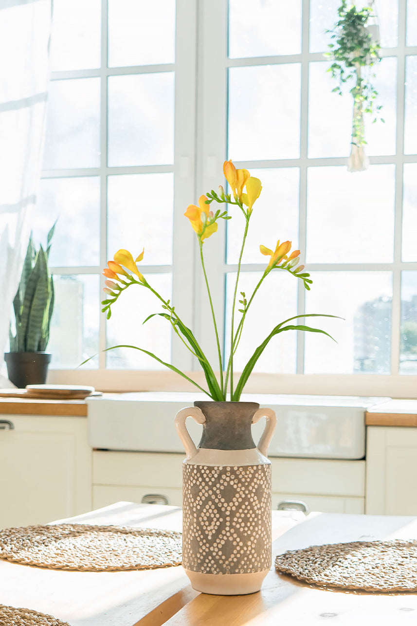 The artificial orange freesia flowers on the dining table with the wooden tone of the home style, adding a warm feeling to the home.